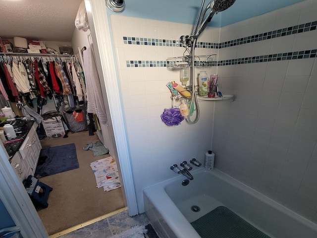 bathroom featuring a textured ceiling and tiled shower / bath