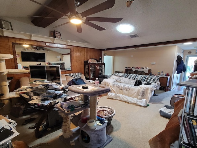 carpeted living room with ceiling fan, a textured ceiling, wooden walls, and vaulted ceiling