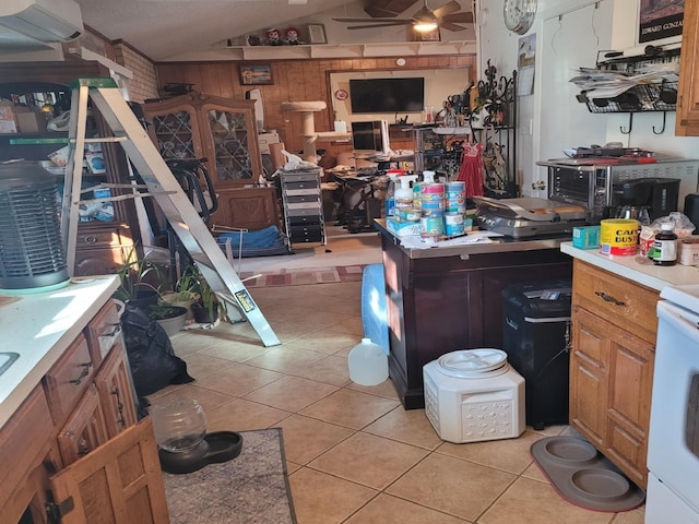 misc room with a workshop area, wood walls, vaulted ceiling, ceiling fan, and light tile patterned flooring