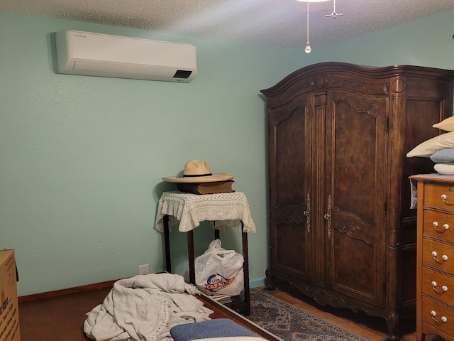 bedroom featuring a wall mounted air conditioner, dark hardwood / wood-style flooring, and a textured ceiling