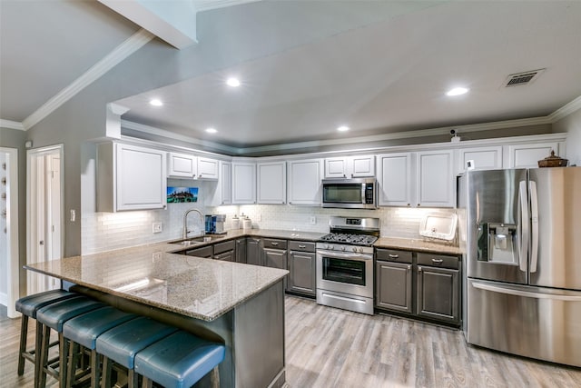 kitchen featuring kitchen peninsula, stainless steel appliances, a breakfast bar, and sink