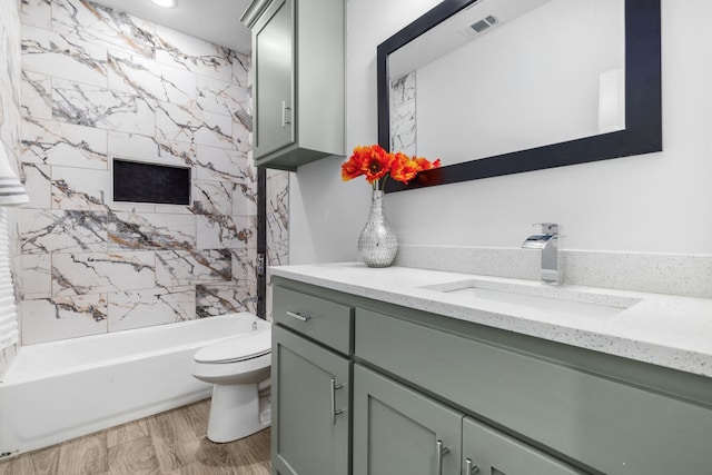 full bathroom with tiled shower / bath, vanity, toilet, and hardwood / wood-style floors