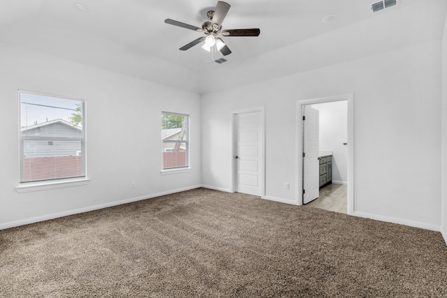 unfurnished bedroom with ensuite bathroom, light carpet, and ceiling fan