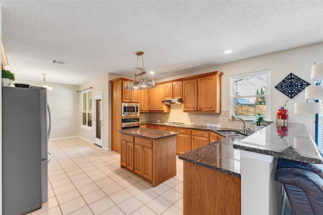 kitchen featuring sink, a kitchen island, dark stone counters, and appliances with stainless steel finishes