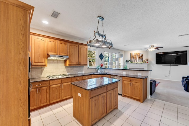 kitchen featuring kitchen peninsula, appliances with stainless steel finishes, sink, a kitchen island, and hanging light fixtures