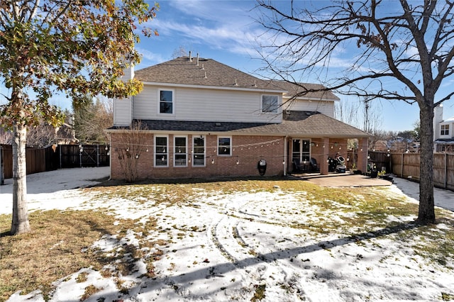 snow covered back of property featuring a patio