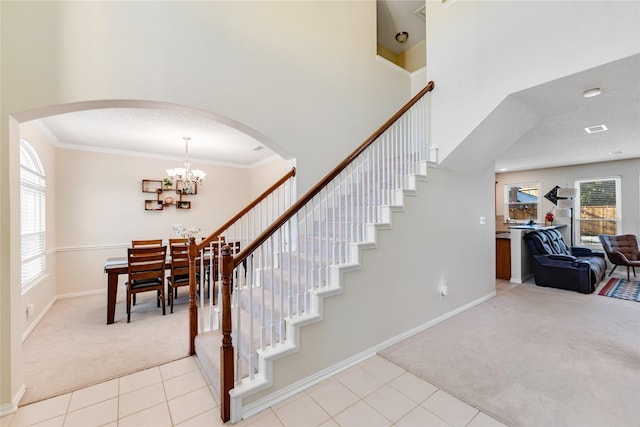 stairs with carpet floors, crown molding, and a notable chandelier