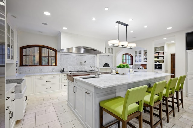 kitchen featuring sink, tasteful backsplash, a spacious island, decorative light fixtures, and a kitchen bar