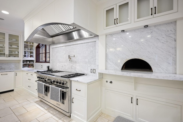 kitchen with decorative backsplash, double oven range, white cabinetry, and range hood