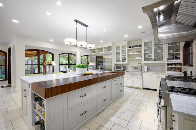 kitchen with white cabinetry, white dishwasher, pendant lighting, island range hood, and a kitchen island