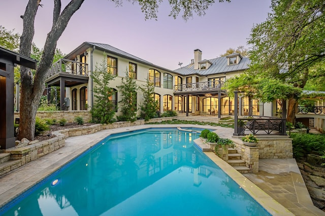 pool at dusk featuring a patio