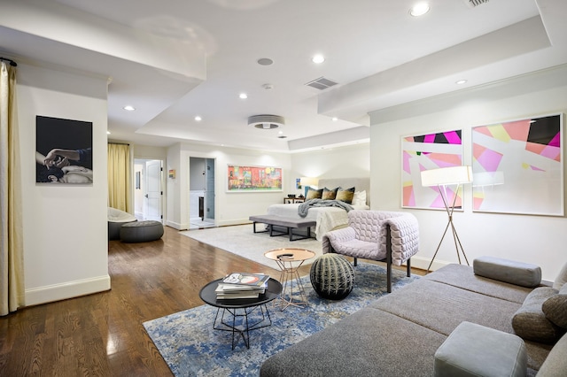 living room with dark wood-type flooring and a tray ceiling