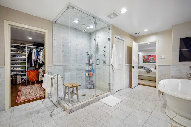 bathroom featuring independent shower and bath and tile walls