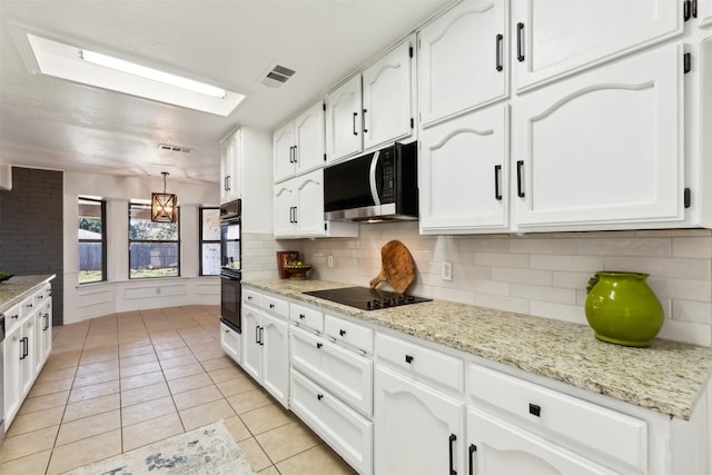 kitchen with light tile patterned floors, backsplash, white cabinetry, and black appliances