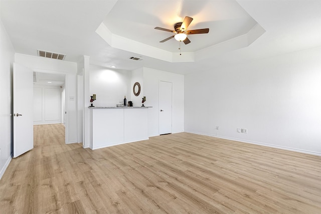 interior space featuring visible vents, a raised ceiling, and light wood finished floors