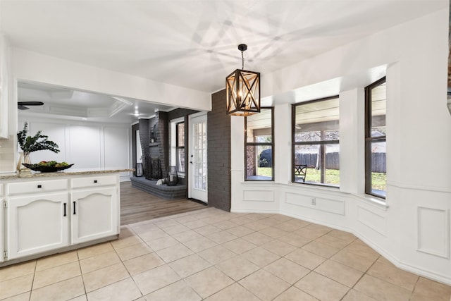 interior space with decorative light fixtures, white cabinetry, a peninsula, a decorative wall, and light tile patterned floors