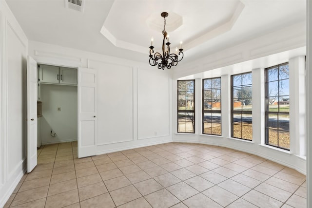 unfurnished dining area featuring a raised ceiling, a decorative wall, and visible vents