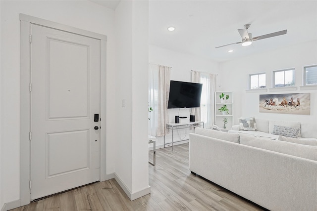 living room featuring ceiling fan, plenty of natural light, and light wood-type flooring