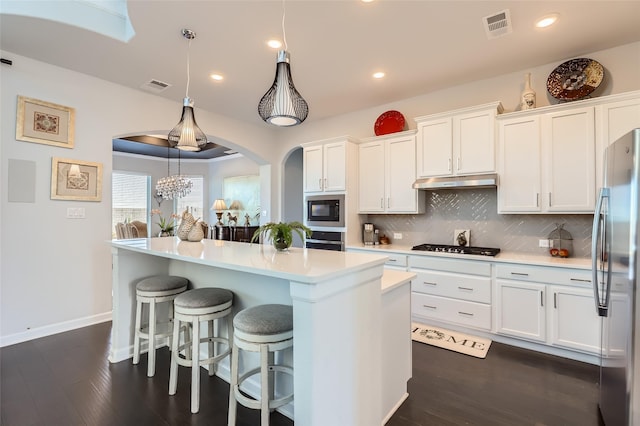 kitchen with decorative light fixtures, a center island, decorative backsplash, white cabinetry, and stainless steel appliances