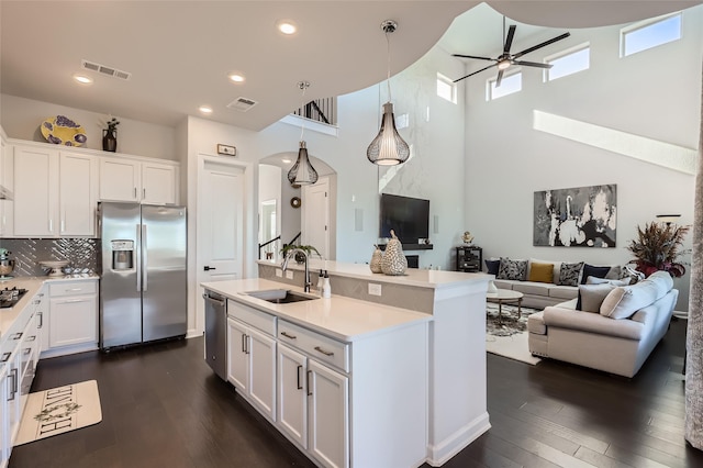 kitchen with decorative backsplash, sink, hanging light fixtures, stainless steel appliances, and white cabinets