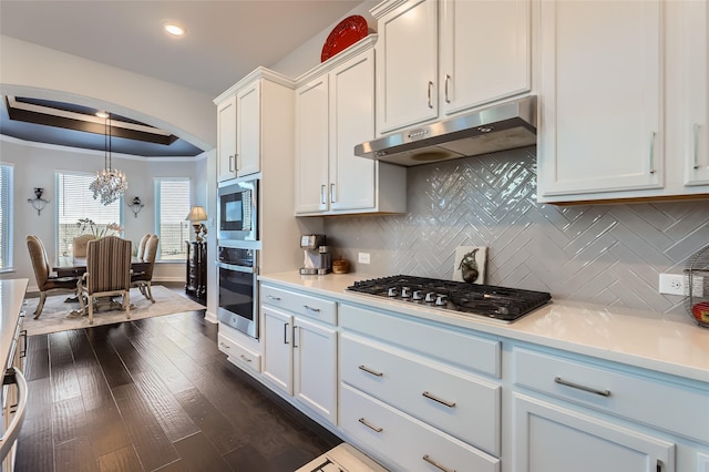 kitchen featuring white cabinetry, stainless steel appliances, backsplash, dark hardwood / wood-style flooring, and pendant lighting