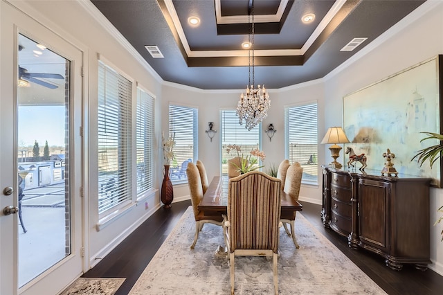 dining space featuring dark hardwood / wood-style flooring, crown molding, ceiling fan with notable chandelier, and a tray ceiling