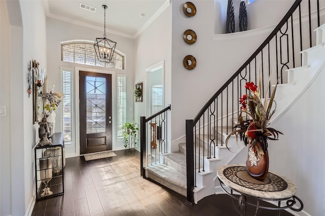 foyer entrance featuring wood-type flooring, crown molding, and an inviting chandelier