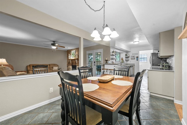 dining area with a fireplace, french doors, and ceiling fan with notable chandelier