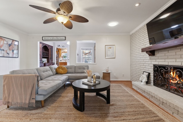 living room with ceiling fan, ornamental molding, a fireplace, and wood-type flooring