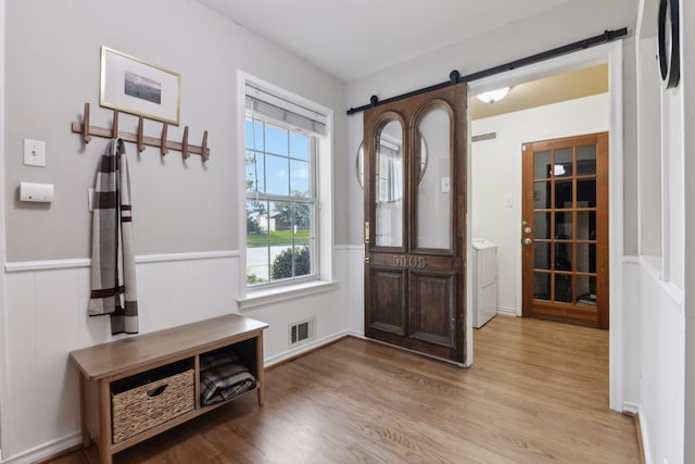 entryway with washer / clothes dryer, light hardwood / wood-style flooring, and a barn door