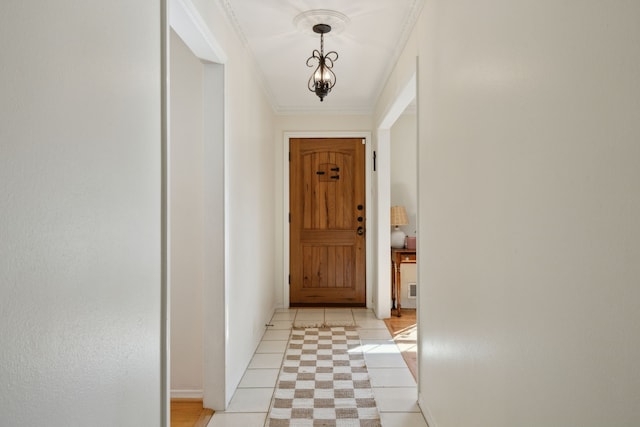 doorway to outside featuring ornamental molding, light tile patterned flooring, and baseboards