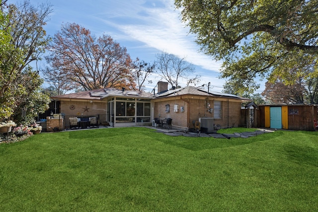 rear view of property with a sunroom, a storage shed, a yard, central air condition unit, and a patio area