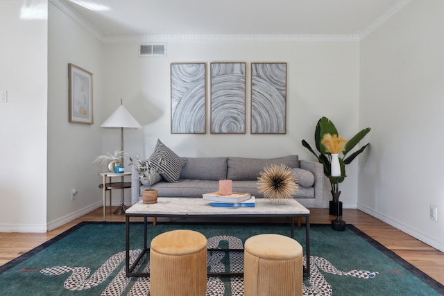 living room with visible vents, crown molding, baseboards, and wood finished floors