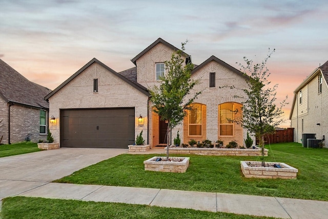 french country inspired facade with brick siding, a lawn, fence, a garage, and driveway