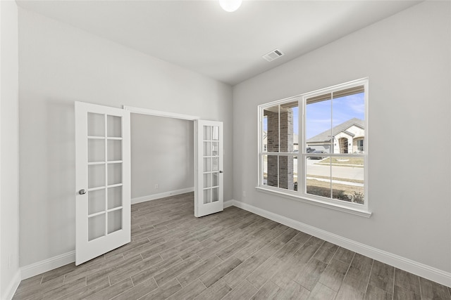 spare room with light hardwood / wood-style floors and french doors