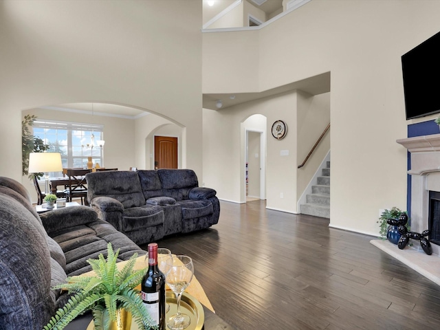 living room featuring a towering ceiling, crown molding, and dark hardwood / wood-style floors