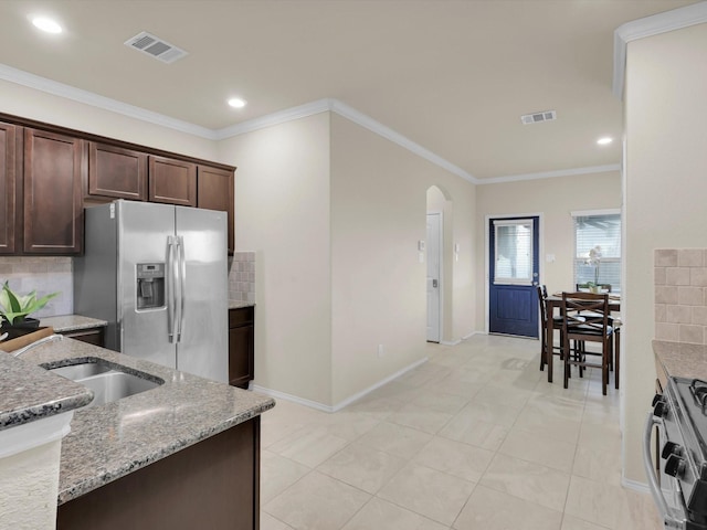 kitchen with ornamental molding, stainless steel appliances, light stone counters, and dark brown cabinetry