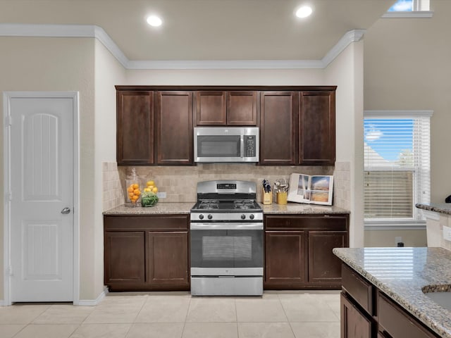 kitchen featuring light stone countertops, appliances with stainless steel finishes, ornamental molding, and light tile patterned floors