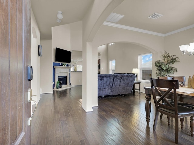 dining area featuring dark wood-type flooring, a notable chandelier, and crown molding