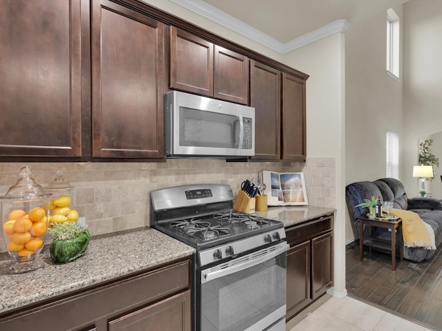 kitchen featuring appliances with stainless steel finishes, crown molding, light stone counters, dark brown cabinetry, and tasteful backsplash