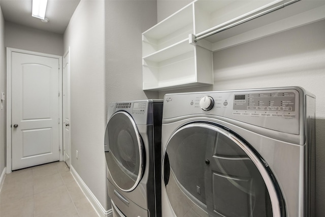 laundry area featuring light tile patterned floors, laundry area, washer and clothes dryer, and baseboards