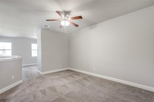 carpeted spare room featuring ceiling fan and a wealth of natural light