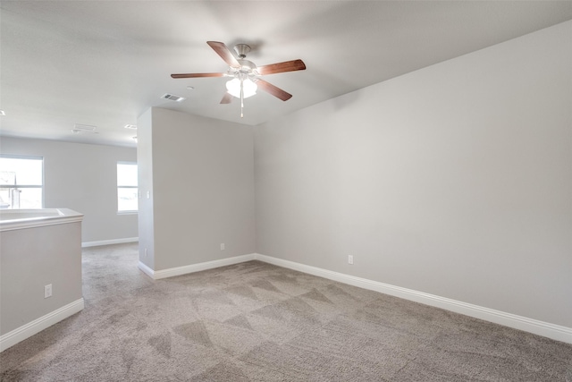 empty room featuring baseboards, visible vents, a ceiling fan, light colored carpet, and a sink