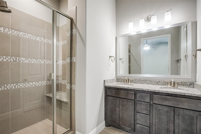 bathroom with a sink, a shower stall, baseboards, and double vanity