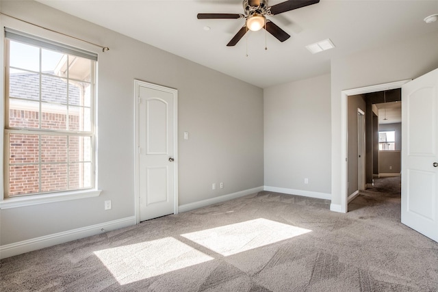 unfurnished bedroom with attic access, multiple windows, baseboards, and light colored carpet