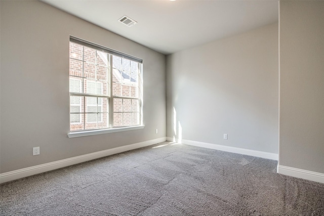 empty room with carpet, visible vents, and baseboards