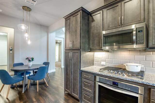 kitchen featuring light stone countertops, tasteful backsplash, pendant lighting, dark brown cabinets, and appliances with stainless steel finishes