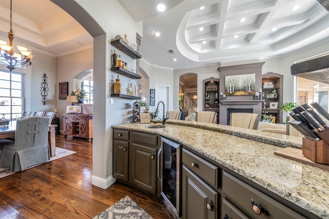 kitchen featuring coffered ceiling, wine cooler, a towering ceiling, ornamental molding, and a chandelier