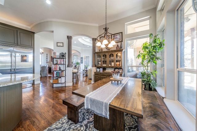 dining area featuring ornate columns, crown molding, a chandelier, and dark hardwood / wood-style floors