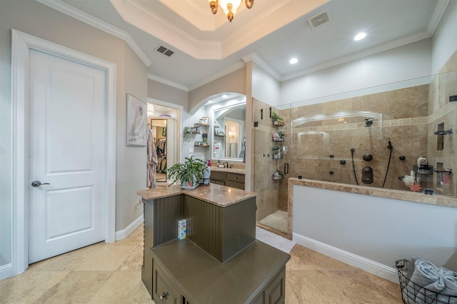 bathroom featuring a tile shower, sink, a tray ceiling, and ornamental molding